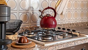 A kitchen with a red kettle, a Nespresso machine, and a granite countertop.