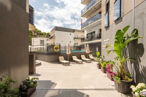 Eine Dachterrasse mit Liegestühlen, einem Pool und Topfpflanzen.