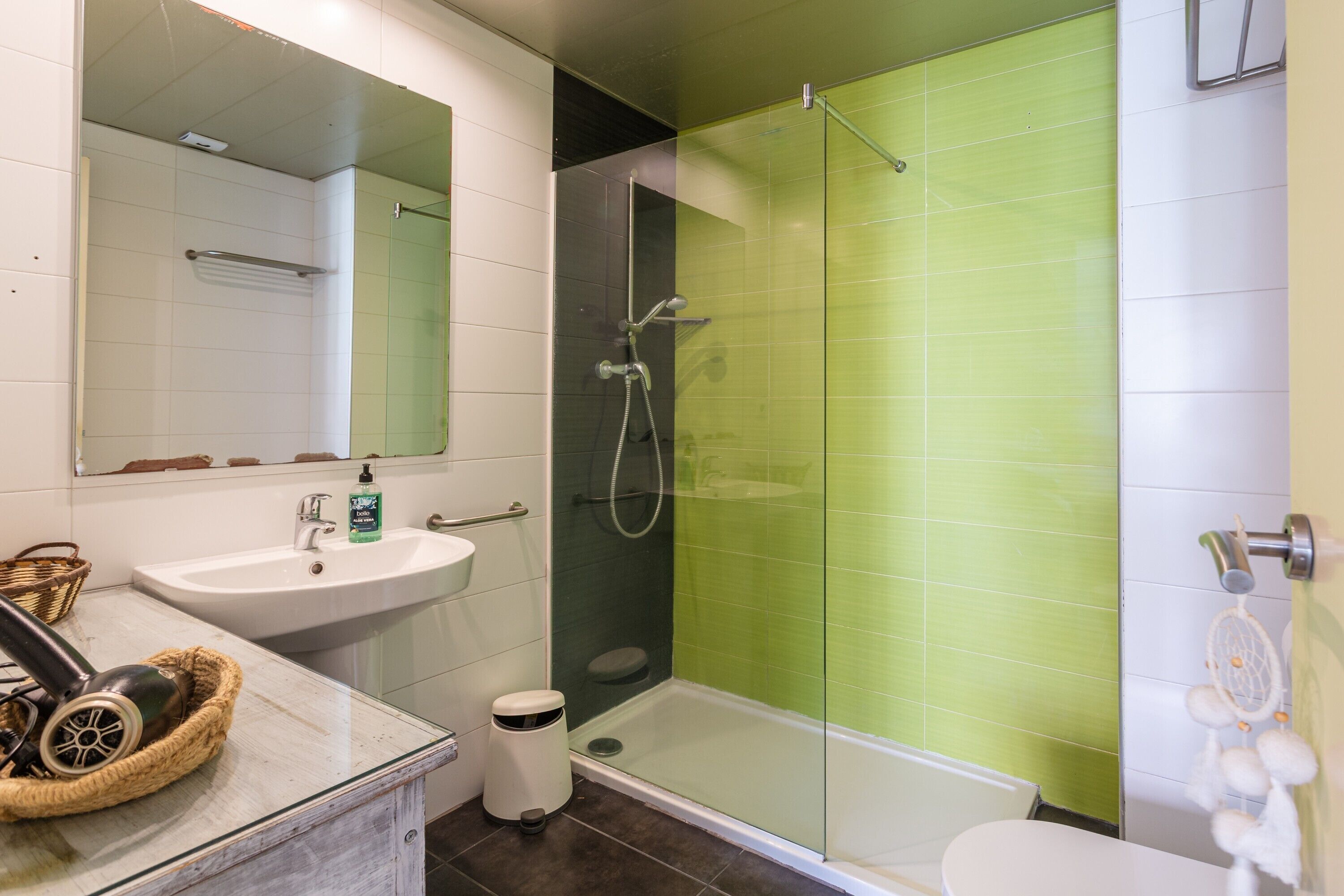 A bathroom with a glass-enclosed shower, a sink, and a toilet.