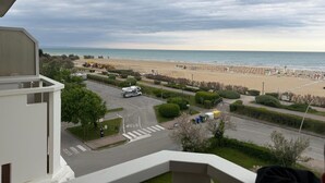 A beach view from a balcony with a parking area and a road leading to the beach. - Sea View Escape at Lido dei Pini (San Michele al Tagliamento)