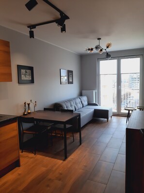 Un espacio habitable moderno con sofá, mesa de comedor, sillas y obras de arte en las paredes.