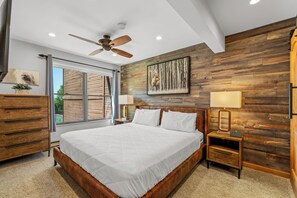 Ein Schlafzimmer mit einem großen Bett, Holzvertäfelung, einem Deckenventilator und einem Fenster mit Blick.