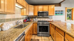 Eine Küche mit Holzschränken, einer Granit Arbeitsplatte, einer Edelstahl-Mikrowelle und einem Backofen.
