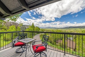 A balcony with a table and chairs, overlooking a scenic landscape with houses and hills. - Slope Day Hideaway | Fireplace & Winter Shuttle (Steamboat Springs)