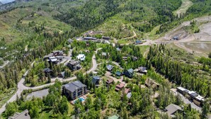 Vista aérea de un complejo turístico con varias construcciones, caminos y montañas al fondo.
