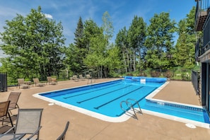 Ein rechteckiger Swimmingpool mit blauer Innenseite, umgeben von Liegestühlen und einer Betonplattform.