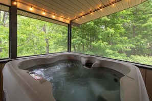 Ein Whirlpool mit Blick auf einen Wald durch große Fenster.