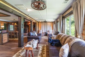 Ein großzügiges Wohnzimmer mit Ledersofas, einem Essbereich und großen Fenstern.