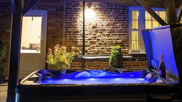 Un jacuzzi iluminado con luz azul, rodeado por un muro de ladrillo y una estructura de madera.