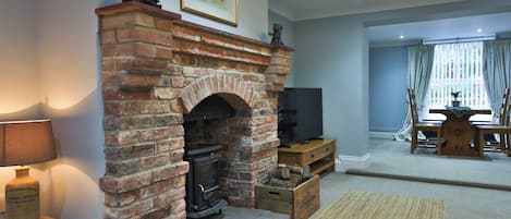 Una sala de estar con chimenea de ladrillo, televisor y comedor con mesa y sillas.