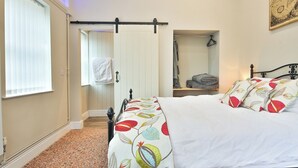 Een slaapkamer met een bed, raam, deur en spiegel.