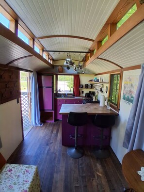 Une cuisine compacte dotée d’un îlot central, de tabourets de bar et d’un réfrigérateur.