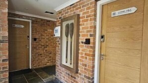 A hallway with brick walls, a wooden door labeled 'Conic Hill,' and a doormat.