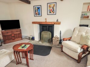 A living room with a fireplace, a television, a sofa, a coffee table, and two framed paintings.