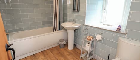 Baño con bañera, lavamanos, inodoro y ventana.
