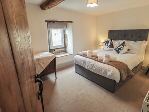 Ein Schlafzimmer mit Bett, Fenster, Nachttisch und Lampe.