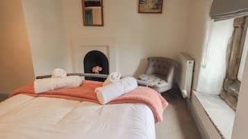 A hotel room with a bed, a chair, a fireplace, and a window.