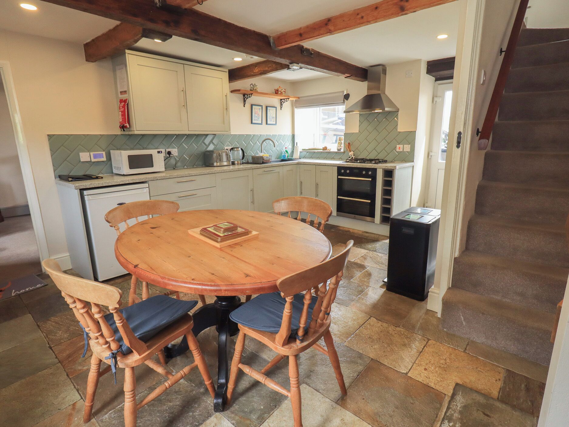Une cuisine avec une table ronde en bois et des chaises, un four à micro-ondes, une cuisinière et des placards.