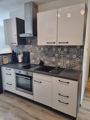 A modern kitchen with white cabinets, a black countertop, a patterned backsplash, and a built-in oven.