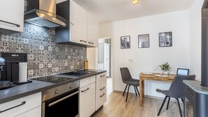 A modern kitchen with a patterned backsplash, stainless steel appliances, and a dining area with a wooden table and chairs. - 'Meini' Holiday Apartment in the Old Train Station (Brilon)