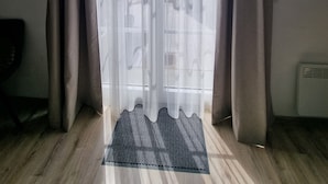 A room with a large sliding glass door, a wooden floor, and a small rug. - 'Meini' Holiday Apartment in the Old Train Station (Brilon)