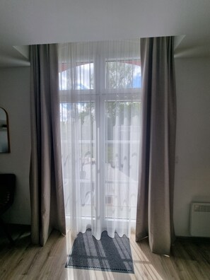 A room with a large sliding glass door, a wooden floor, and a small rug. - 'Meini' Holiday Apartment in the Old Train Station (Brilon)