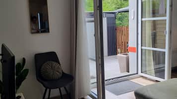 A modern living room with a television, a chair, a sofa, and a sliding glass door leading to an outdoor area.