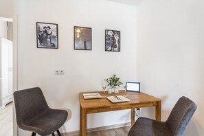 Un comedor con una mesa de madera, dos sillas y tres cuadros en la pared.