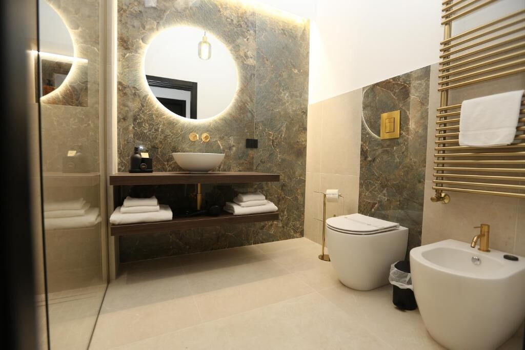 Un baño moderno con un espejo redondo, un lavabo sobre encimera, un inodoro y un bidé.