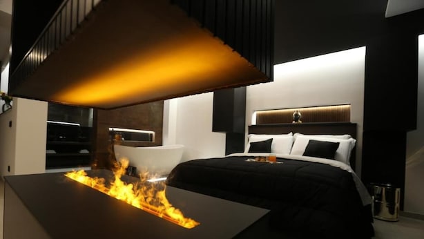 Un dormitorio moderno con cama, mesita de noche y una mesa con efecto de fuego.