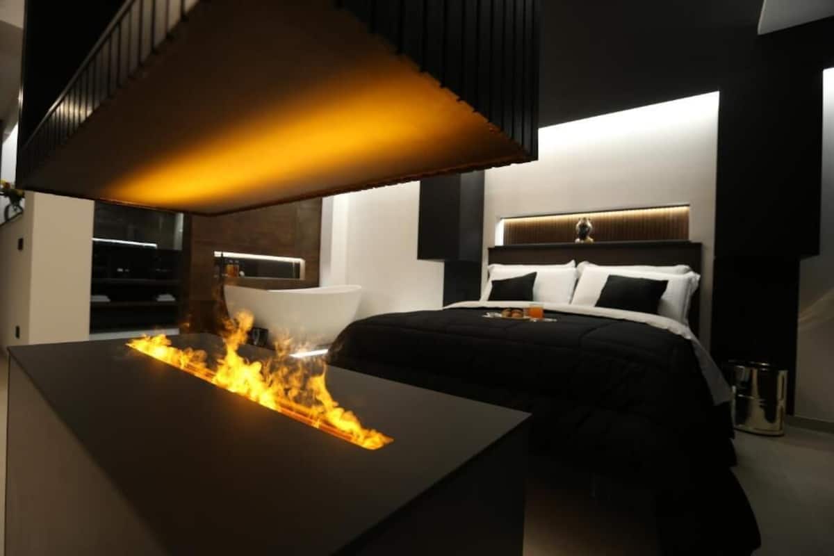 A modern bedroom with a bed, bedside table, and a unique feature of a table with a fire effect.