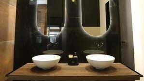 Un baño con dos lavamanos, un espejo grande y un perchero para toallas.