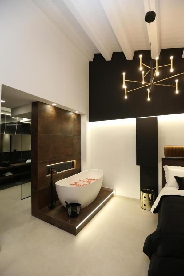 A modern bathroom with a freestanding bathtub, a large mirror, and a unique geometric light fixture.