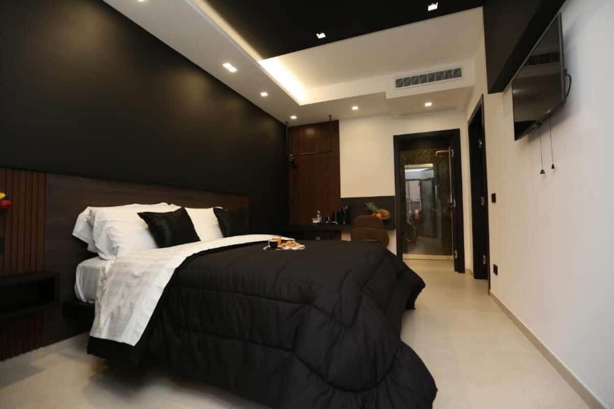 A modern bedroom with a black bed, white bedding, and a wooden headboard.