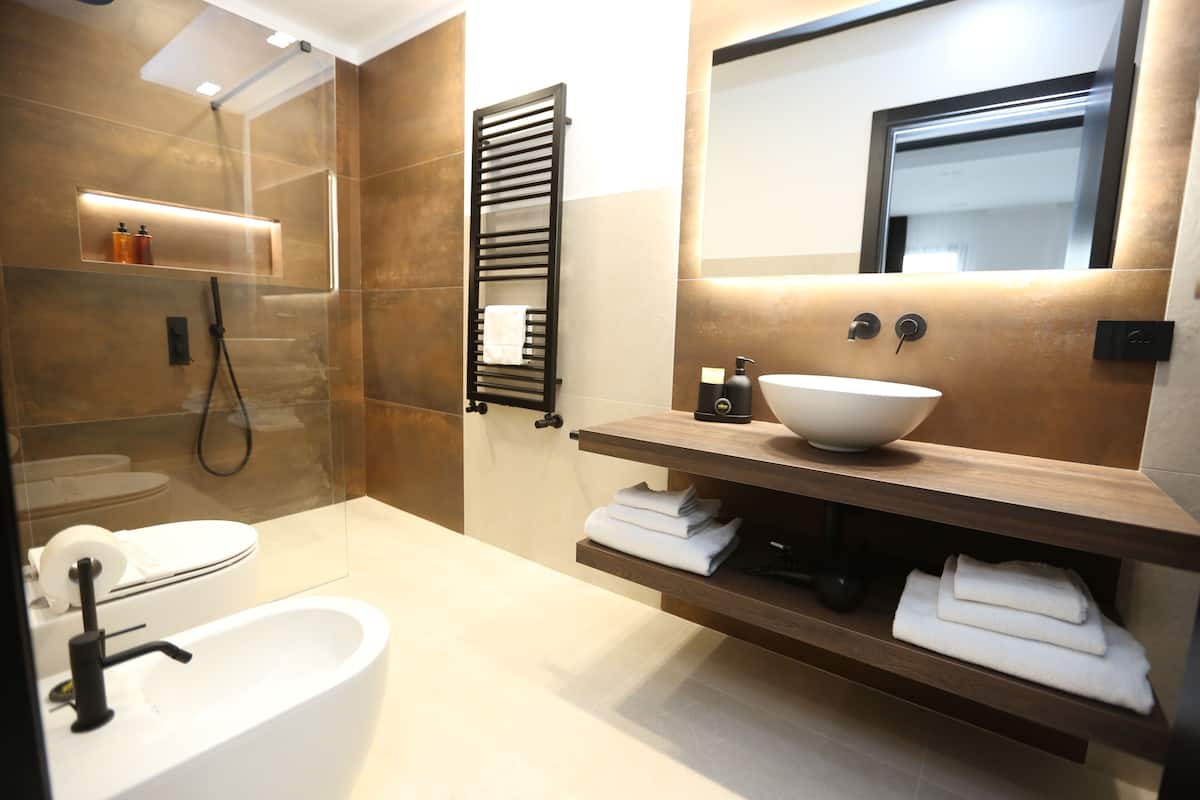 A modern bathroom with a freestanding bathtub, a large mirror, and a wooden vanity with a bowl sink.
