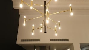 Una cocina moderna con una isla central, iluminación colgante y una pared de acento oscura.