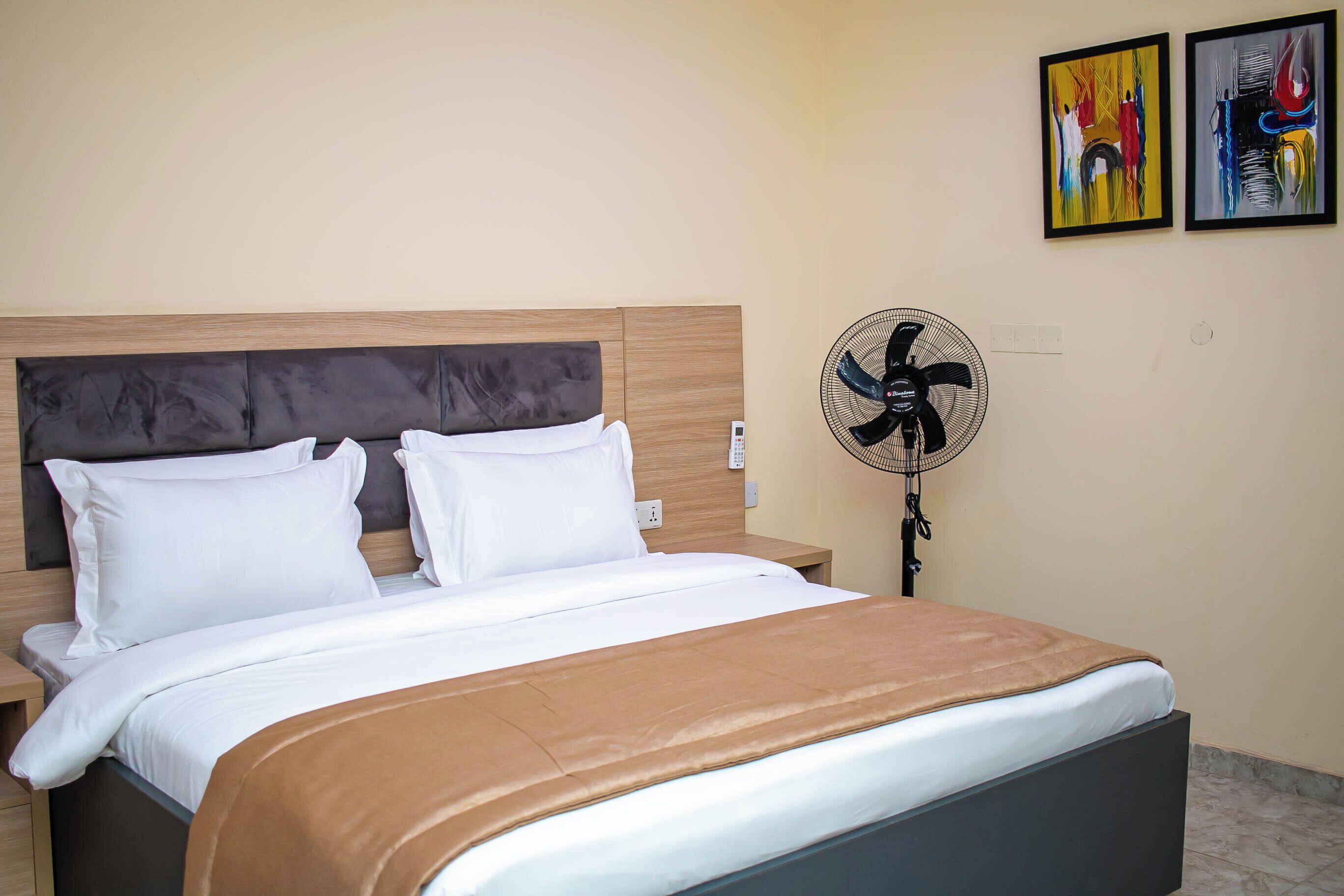 Una cama bien hecha con una manta marrón, un cabecero de madera y almohadas blancas.