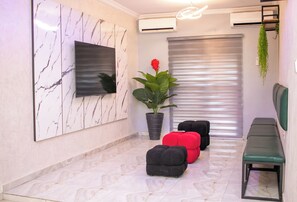 A modern interior with a marble wall, a mounted TV, a potted plant, and a bench. - Cedar Suites (Ibadan)