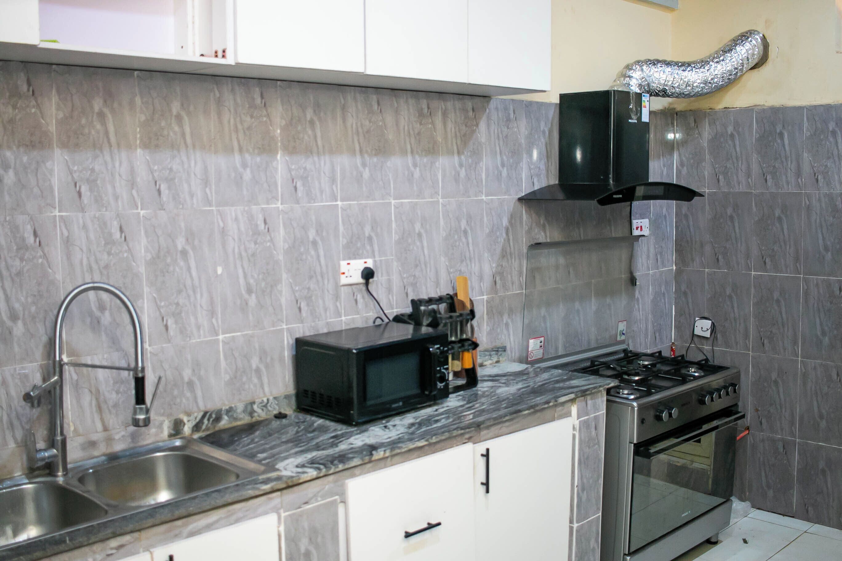 Una cocina con un lavamanos de acero inoxidable, microondas, estufa y cocina a gas.