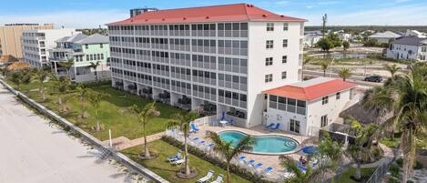 Un hotel con piscina, varios pisos y techo rojo.
