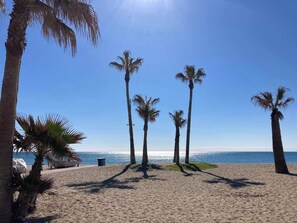 A beach with palm trees and a clear sky. - Cozy One-Bedroom Apartment with Terrace and Sea Views (Mijas-Costa)