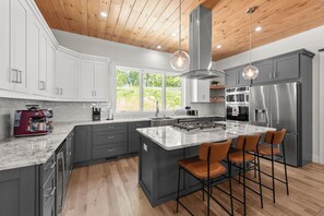 Una cucina moderna con un'isola grande, elettrodomestici in acciaio inossidabile e soffitto in legno.