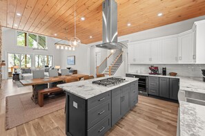 Una cucina moderna con isola centrale, soffitto in legno e mobili bianchi.