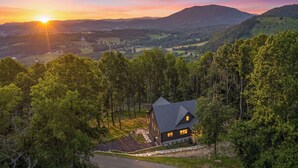 Una casa amb un teulat pronunciat, envoltada d'arbres, situada en un paisatge amb pendent.
