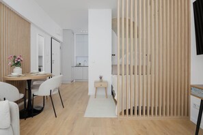 Ein modernes Zimmer mit Essbereich, einem kleinen Nachttisch und einer Holzwand.