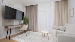 Ein modernes Wohnzimmer mit Flachbildfernseher, Schreibtisch mit Stuhl, Sofa und Couchtisch.
