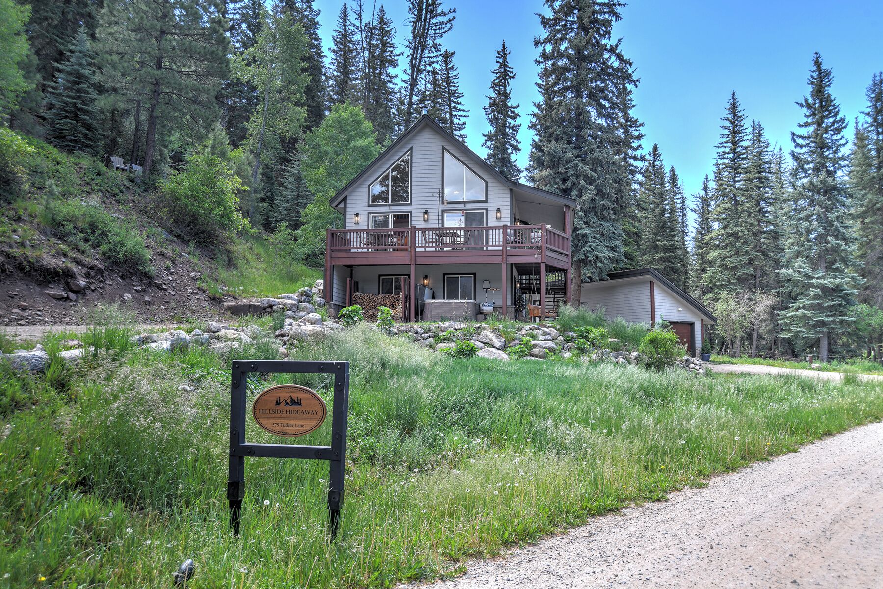 Eine zweistöckige Lodge mit Balkon, umgeben von einem Wald.