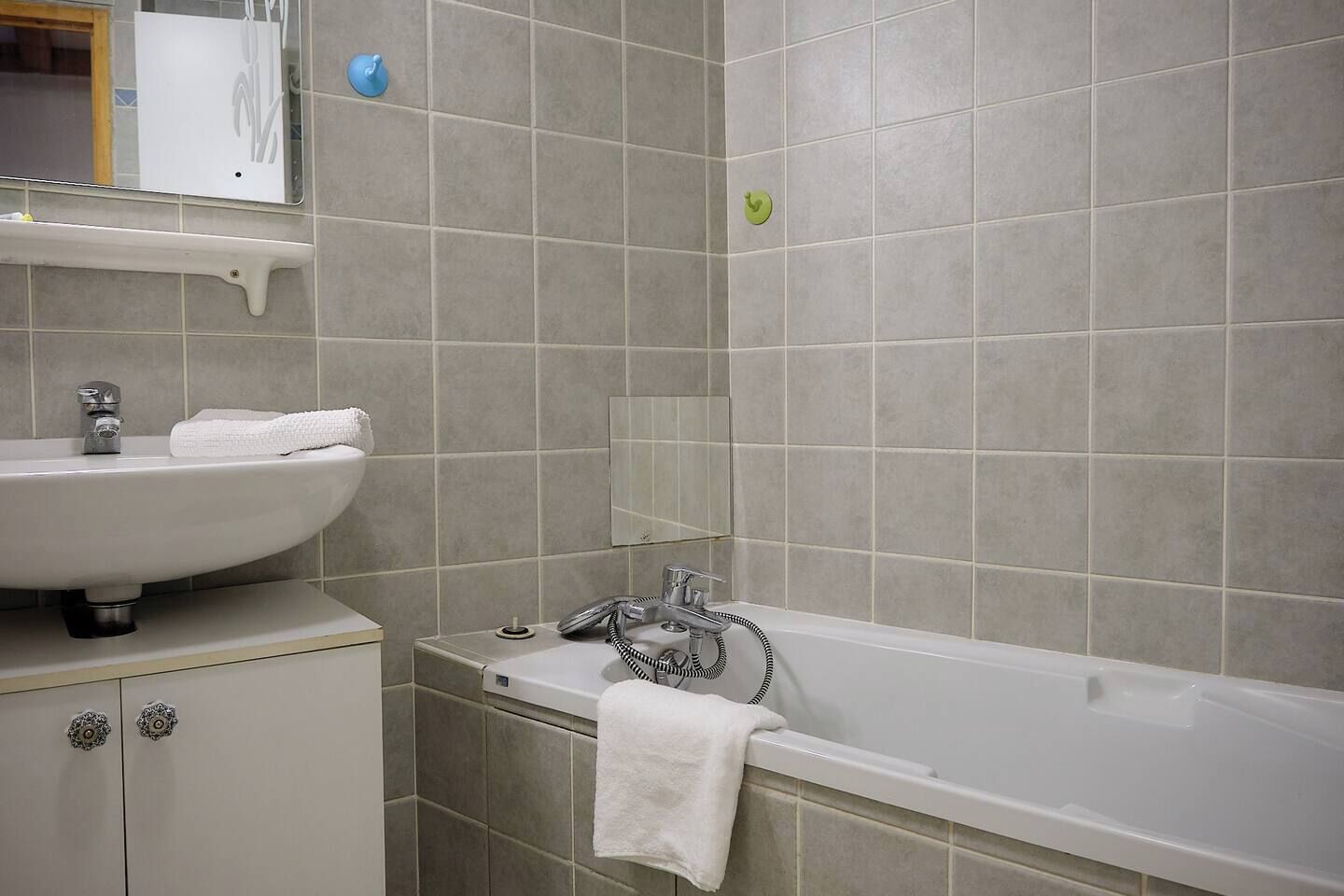 A bathroom with a sink, mirror, and bathtub.