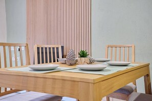 Een eettafel met vier witte borden, twee houten stoelen, een kleine potplant en een decoratieve dennenappel.