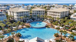 Ein Resort mit einem zentralen Schwimmbad, mehreren Balkonen und Palmen.